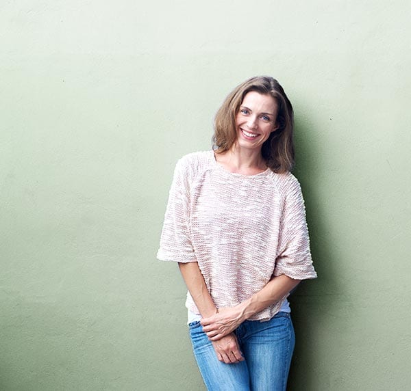 an attractive middle aged woman against a pale green wall