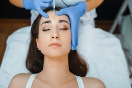 a young woman getting botox injected into her forehead
