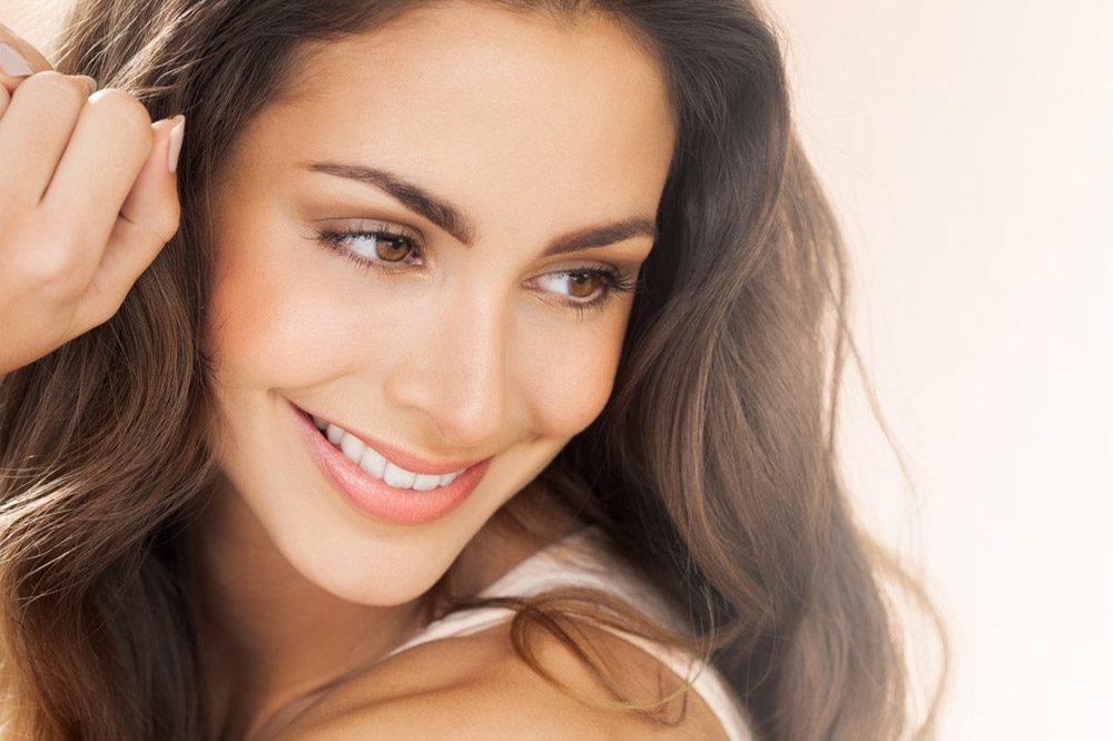 A woman with long brown hair is smiling at a Cincinnati Wellness Center.