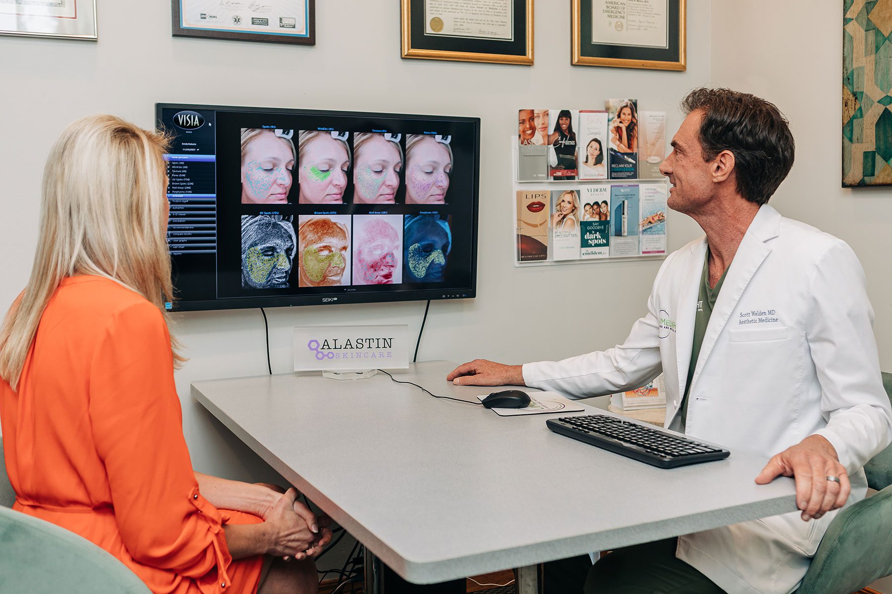 A man and woman at a table, engaged in a wellness services discussion while looking at a computer screen.