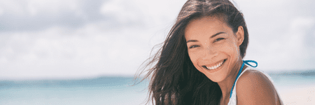 A woman smiling on the beach during her wellness retreat at Limelight Medical Spa.